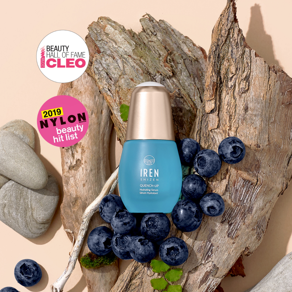 A blue QUENCH-UP Hydrating Serum bottle by IREN Shizen is surrounded by blueberries, driftwood, stones, and CLEO and NYLON award stickers—ideal for plump skin with Hyaluronic Acid.
#all-groups