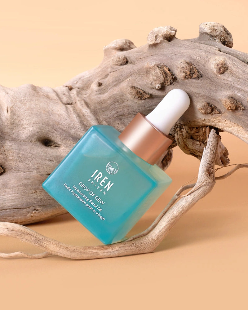 A blue dropper bottle labeled "IREN Shizen" containing DROP OF DEW Moisturizing Facial Oil for skin barrier repair rests on textured driftwood against a beige background.
#all-groups