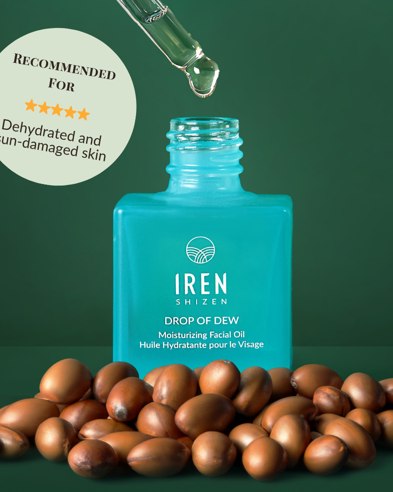 A blue bottle of IREN Shizen DROP OF DEW Moisturizing Facial Oil with a dropper above and argan nuts in front; the label highlights its recommendation for dehydrated and sun-damaged skin, supporting effective skin barrier repair.
