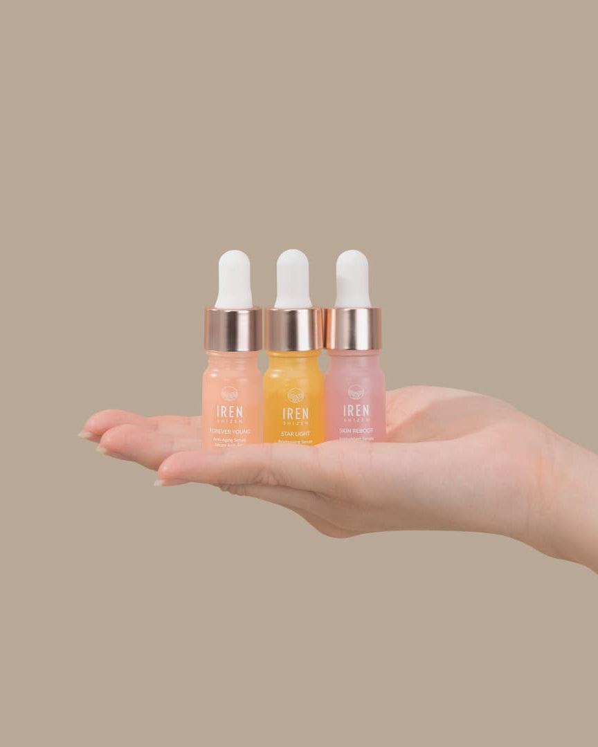 A person's hand holding the GLOW UP Anti-Aging Discovery Kit by IREN Shizen, consisting of serum minis.