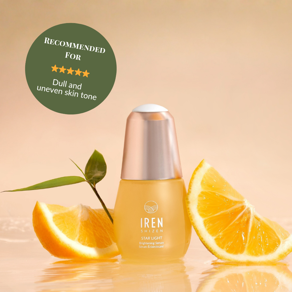 A bottle of IREN Shizen STAR LIGHT Brightening Serum is shown with orange slices and a green leaf. The label suggests it for dull, uneven skin tone and dark spots to promote a naturally radiant complexion. #show-lang-en