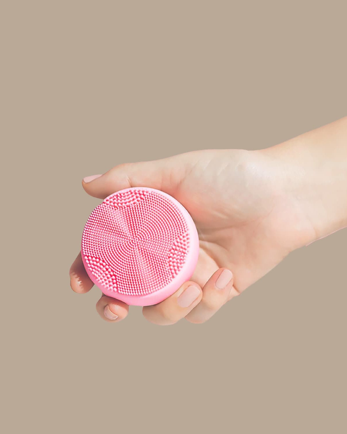 A person's hand holding a SKIN GENIE PRO Cleansing Brush for customized Japanese skincare on a beige background.