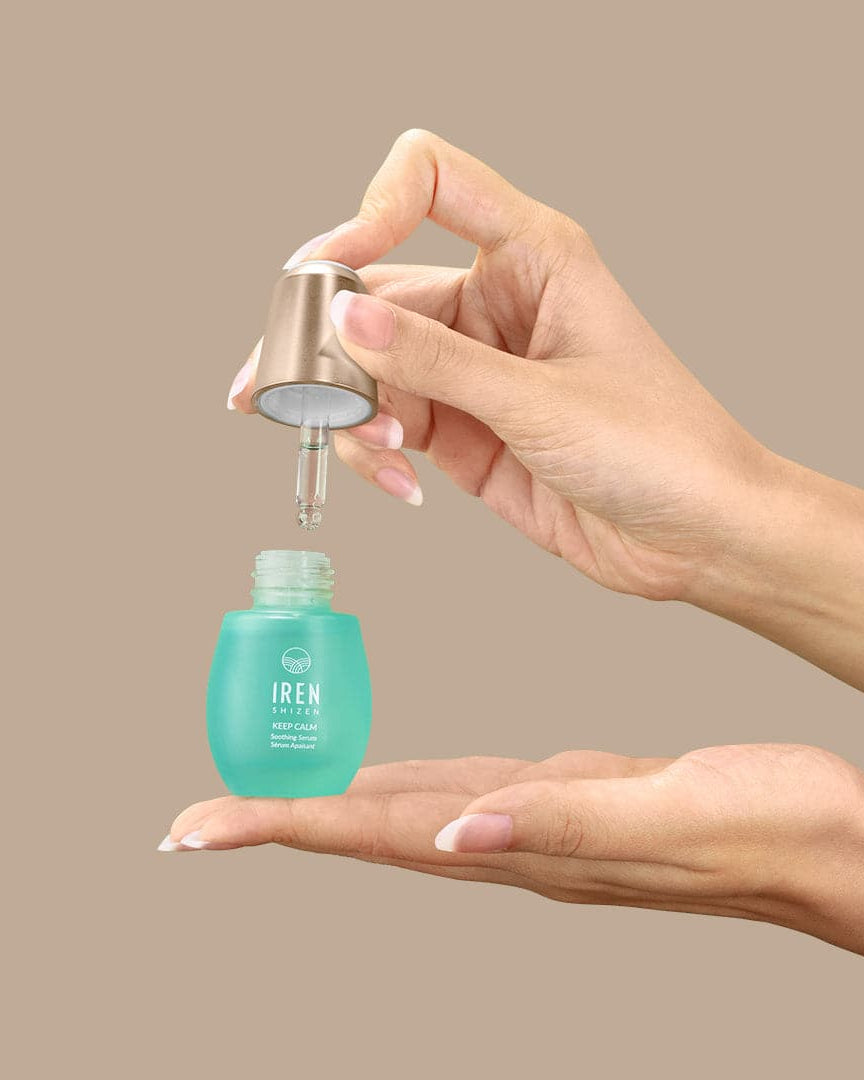 A woman's hand holding a bottle of customised KEEP CALM Soothing Serum by IREN Shizen, inspired by Japanese and onsen skincare. #all-groups