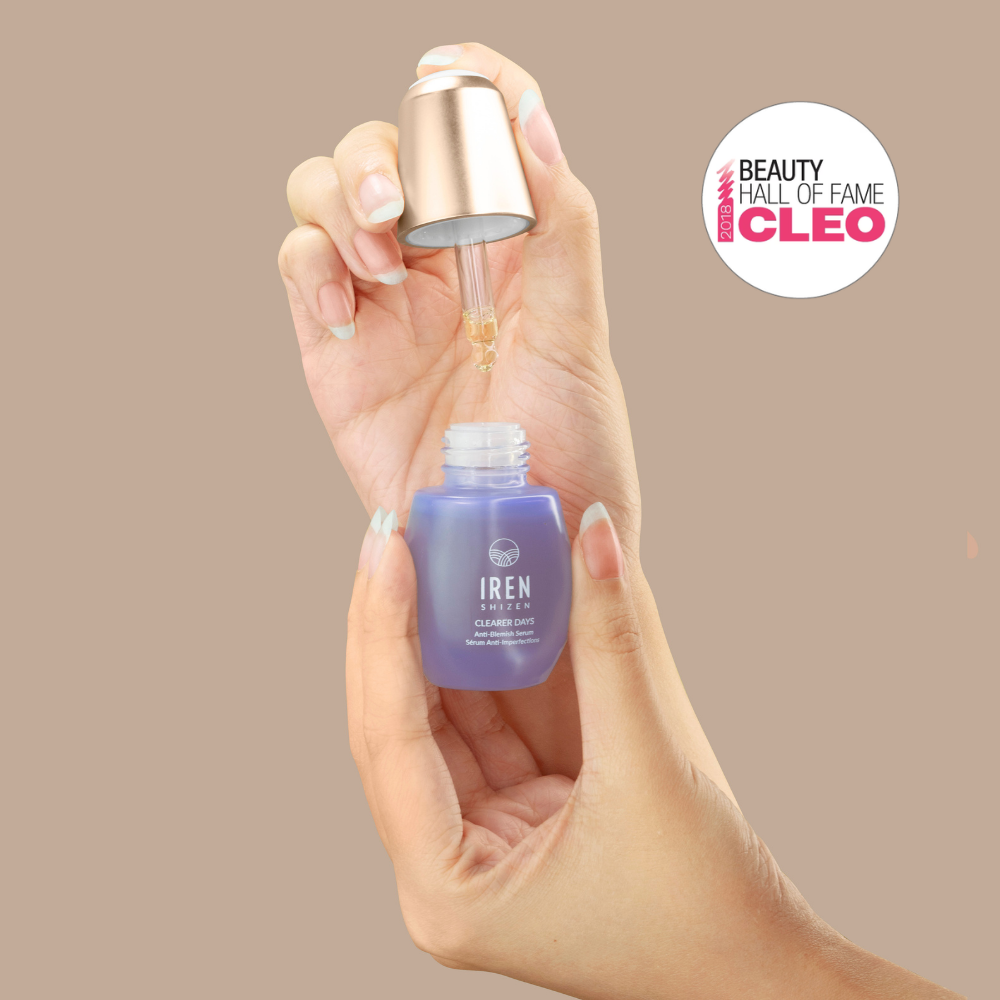 A hand holds a dropper above a blue FRESH AND CLEAR Cleansing Kit bottle from Fast Bundle, with a Beauty Hall of Fame award badge in the background—perfect for your skincare routine.