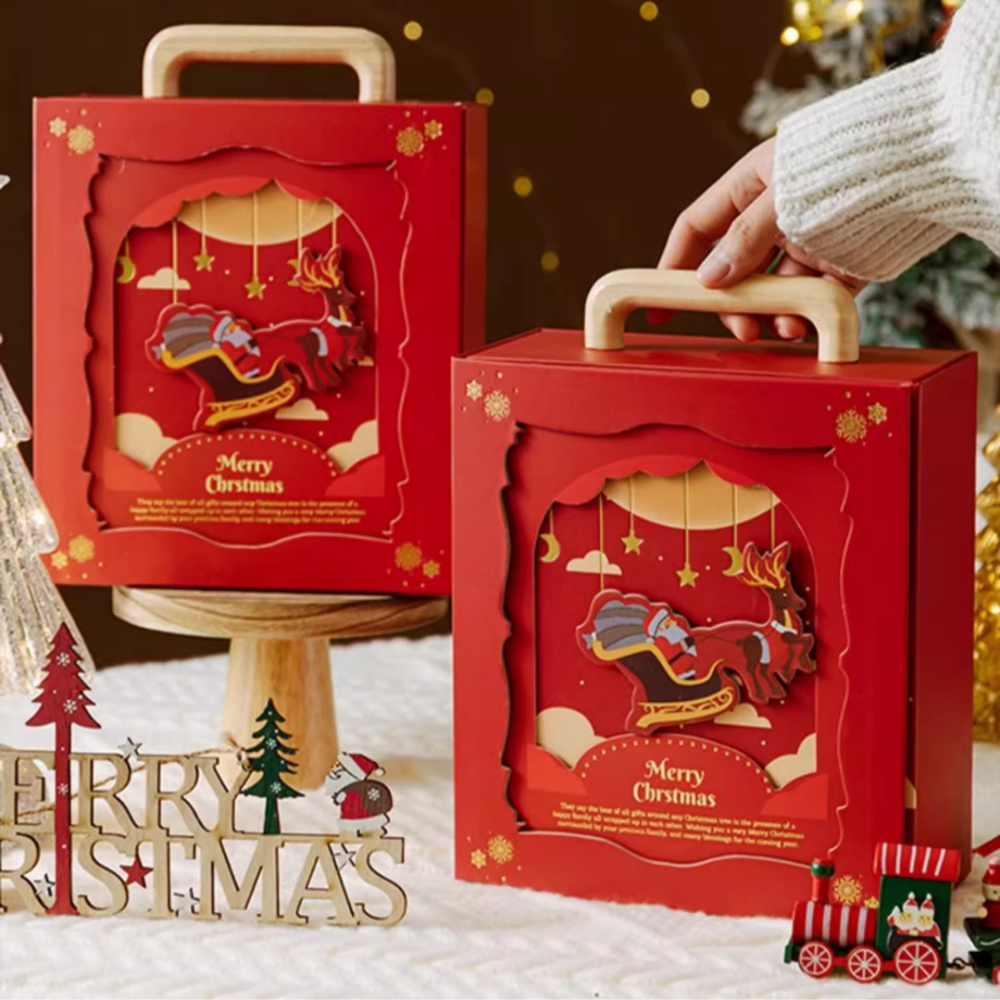 Two FOR SPECIAL ONES Xmas Santa Claus Gift Boxes from IREN Shizen, featuring a reindeer sleigh design. One box is being held, surrounded by Christmas decorations, including a Merry Christmas sign and a small train.