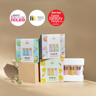 Four IREN Shizen GLOW UP Anti-Aging Discovery Kits and three award logos arranged on a beige surface with a light brown background. These kits include an anti-aging serum with natural ingredients for collagen-boosting benefits.