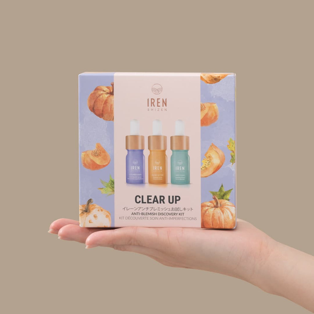 A hand holding a CLEAR UP Anti-Blemish Discovery Kit with pumpkins on it, perfect for improving complexion with the power of superfruits. Brand: IREN Shizen