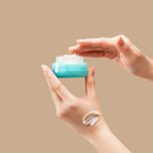 A person holding a jar of FREEZE THE YOUTH Hydra Firming Cream from IREN Shizen. all-groups