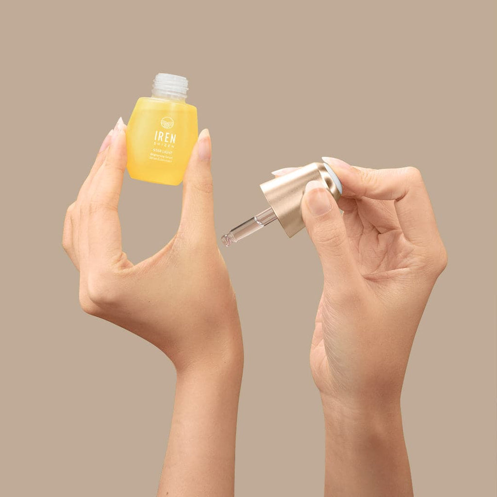 A woman's hands holding a small bottle of customised IREN Shizen STAR LIGHT Brightening Serum.
