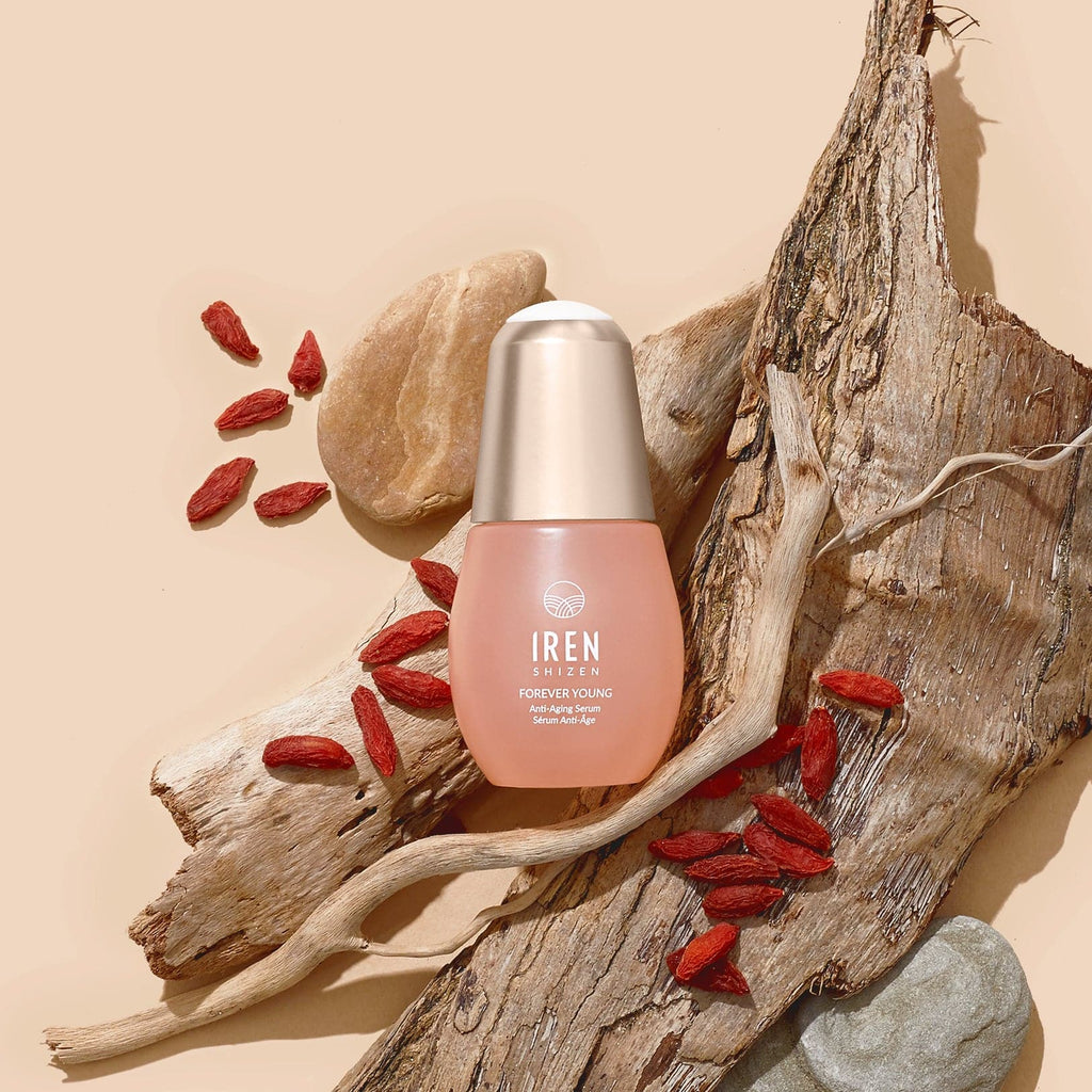 A bottle of customised FOREVER YOUNG Anti-Aging Serum by IREN Shizen, inspired by Japanese skincare, on a beige background.